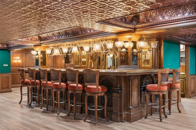 bar with light wood-type flooring and crown molding