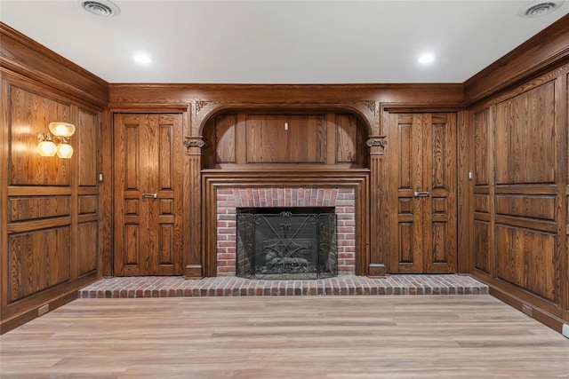 unfurnished living room with a brick fireplace, light hardwood / wood-style floors, and wooden walls