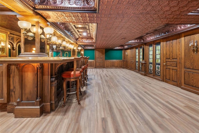 bar featuring light hardwood / wood-style flooring, wood walls, and ornamental molding