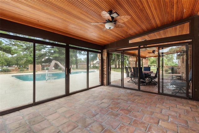 unfurnished sunroom featuring ceiling fan, lofted ceiling, wooden ceiling, and a healthy amount of sunlight