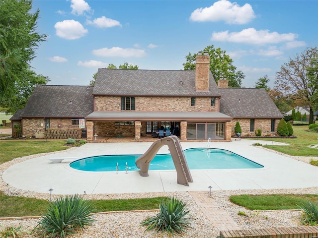 view of pool with a lawn, a patio, a water slide, and a diving board