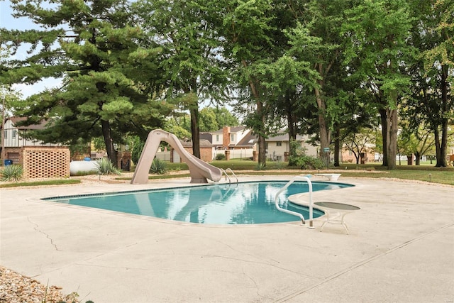 view of pool featuring a diving board, a water slide, and a patio area