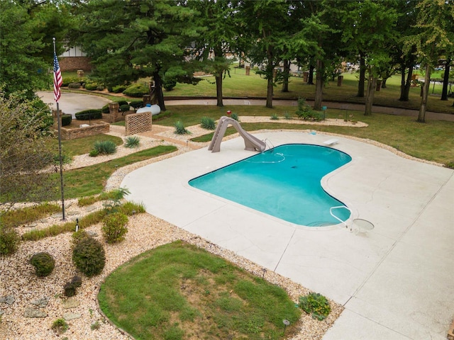 view of pool featuring a diving board, a water slide, a patio area, and a yard