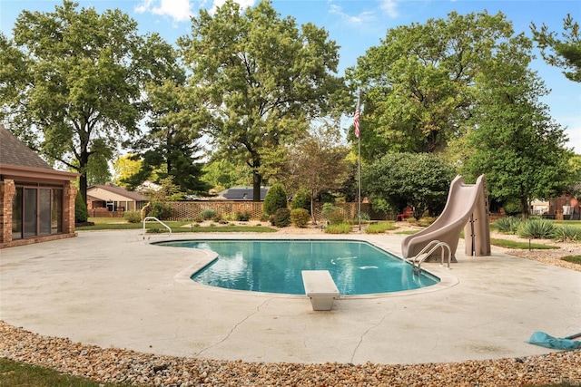 view of swimming pool featuring a patio, a water slide, and a diving board