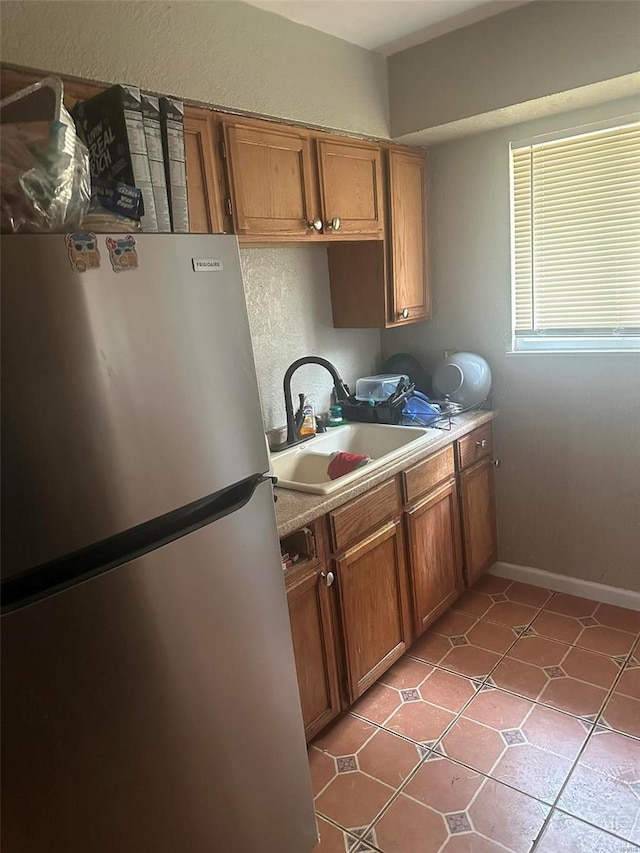 kitchen featuring stainless steel fridge, light tile patterned flooring, and sink