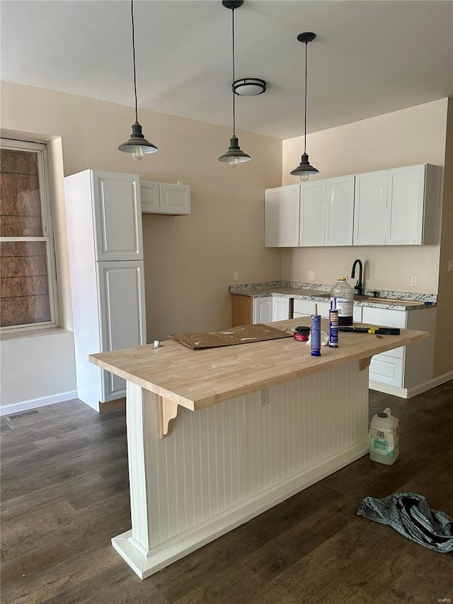 kitchen with white cabinetry, decorative light fixtures, wooden counters, a kitchen island, and dark hardwood / wood-style floors