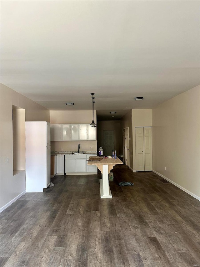 kitchen featuring a kitchen breakfast bar, dark hardwood / wood-style flooring, hanging light fixtures, sink, and white cabinets