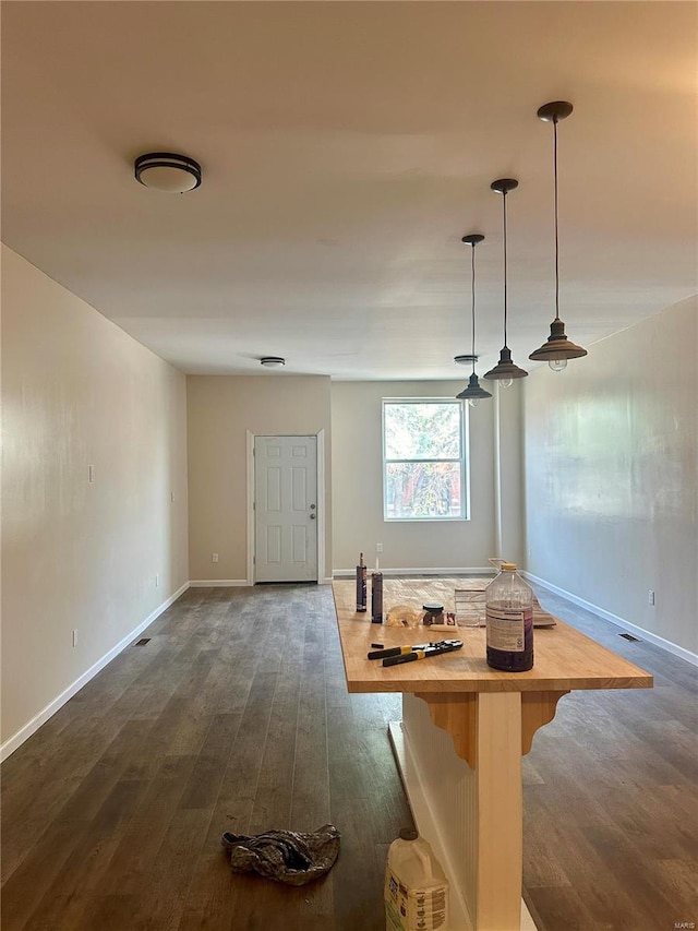 interior space featuring pendant lighting, butcher block countertops, and dark hardwood / wood-style floors