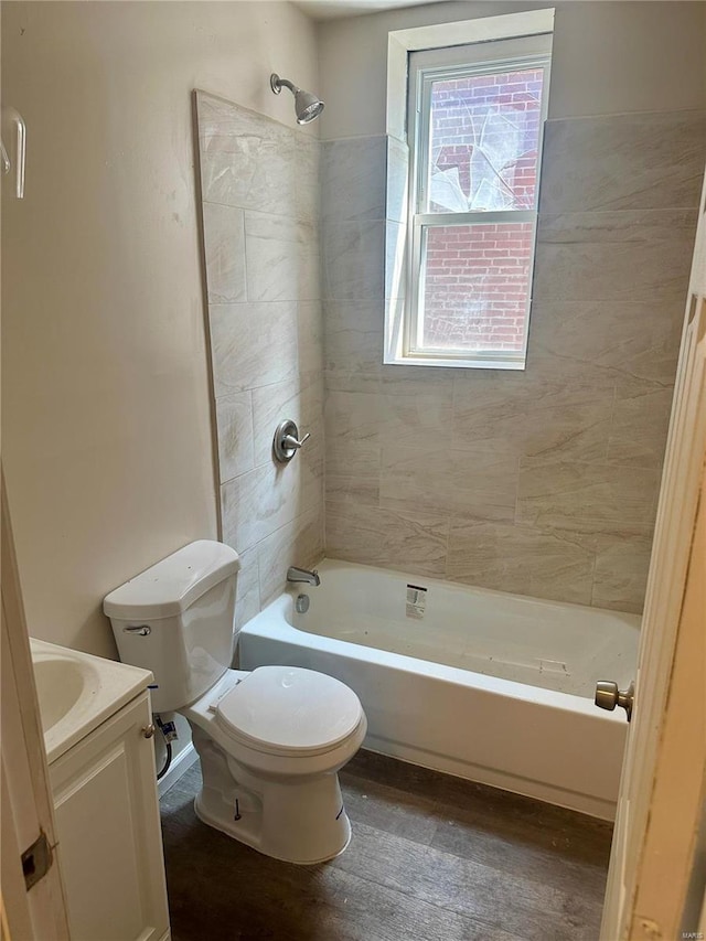 full bathroom with tiled shower / bath combo, vanity, toilet, and wood-type flooring