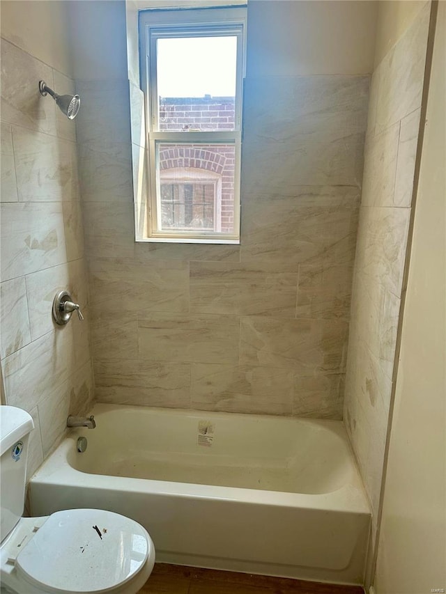 bathroom featuring toilet and tiled shower / bath combo