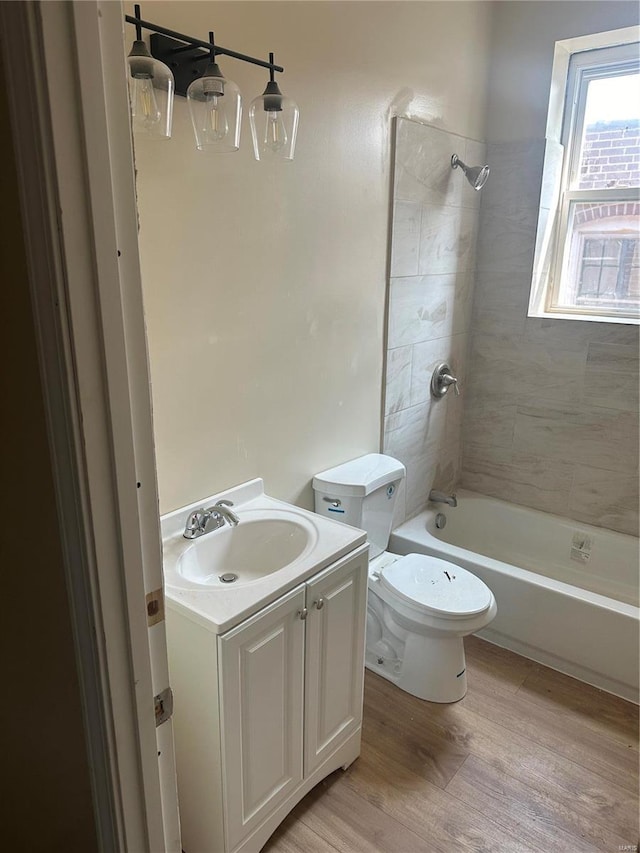 full bathroom with tiled shower / bath combo, vanity, toilet, and hardwood / wood-style flooring