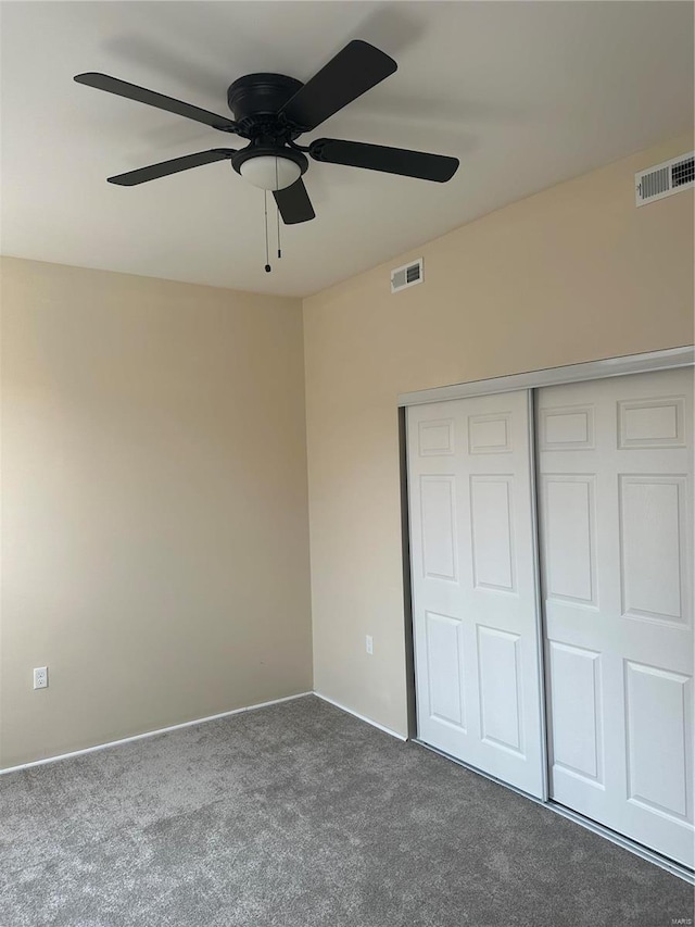 unfurnished bedroom with dark carpet, ceiling fan, and a closet