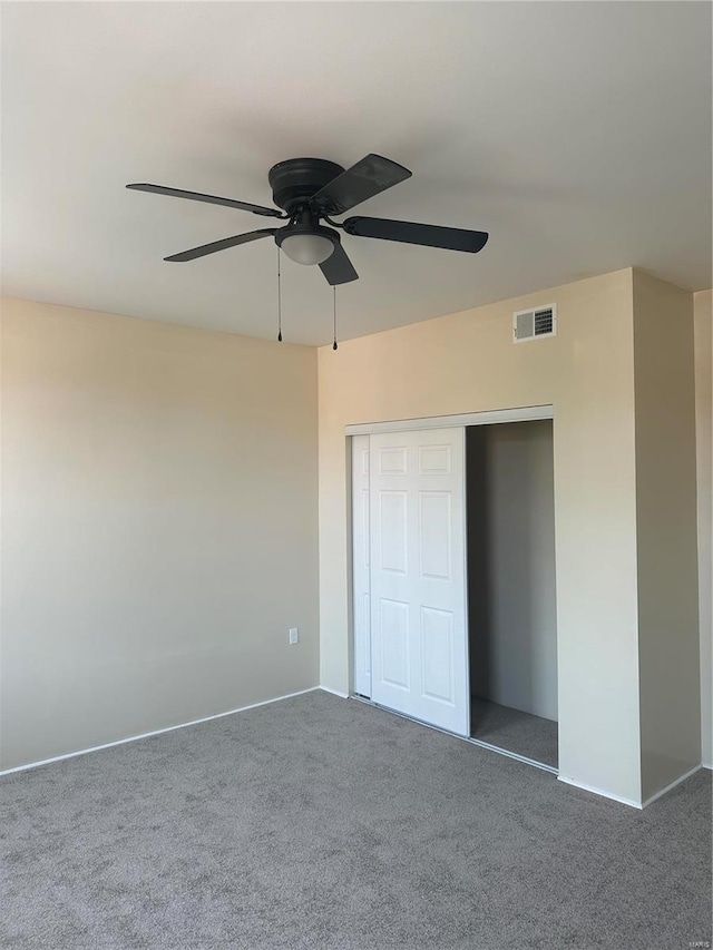 unfurnished bedroom with dark carpet, ceiling fan, and a closet