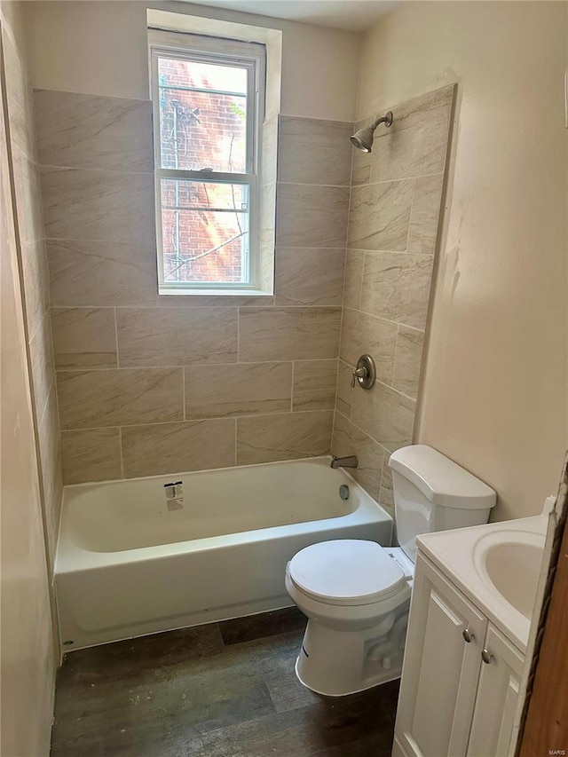 full bathroom with wood-type flooring, toilet, tiled shower / bath combo, and vanity