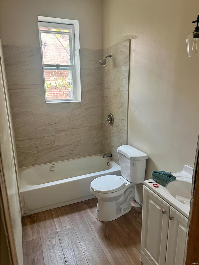 full bathroom featuring wood-type flooring, toilet, tiled shower / bath combo, and vanity