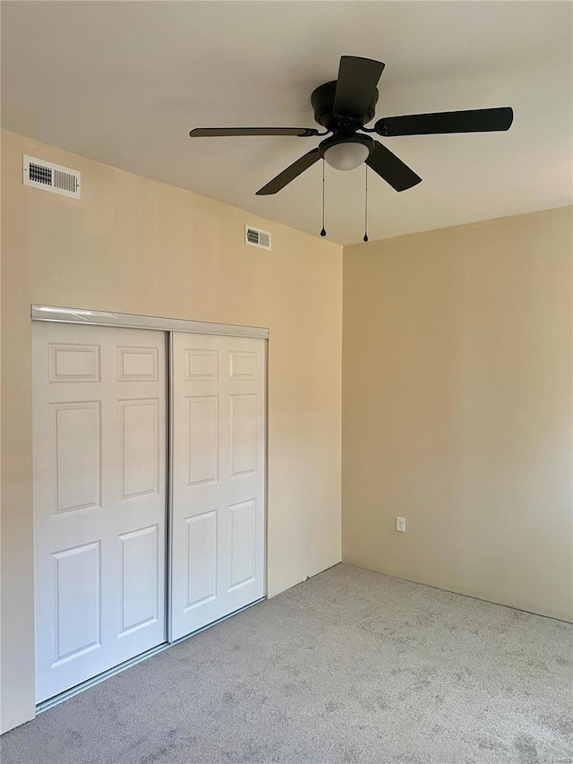 unfurnished bedroom featuring light colored carpet, ceiling fan, and a closet