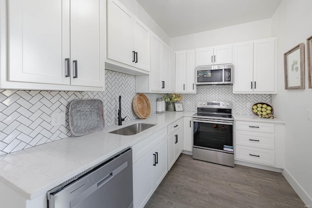 kitchen with appliances with stainless steel finishes, tasteful backsplash, light hardwood / wood-style floors, sink, and white cabinets