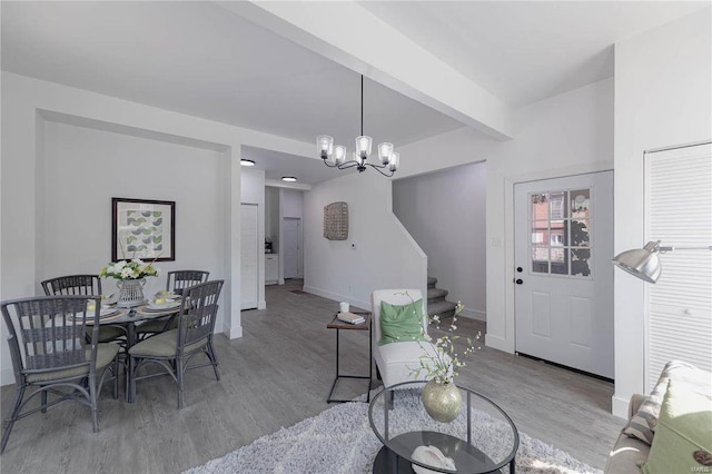 dining space featuring a notable chandelier, beam ceiling, and hardwood / wood-style flooring