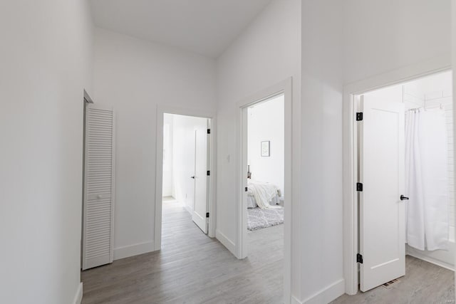 corridor with a towering ceiling and light wood-type flooring