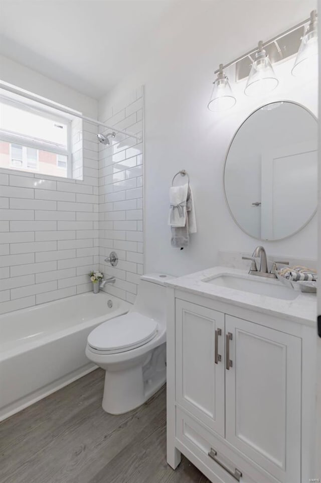 full bathroom with tiled shower / bath, vanity, toilet, and hardwood / wood-style flooring