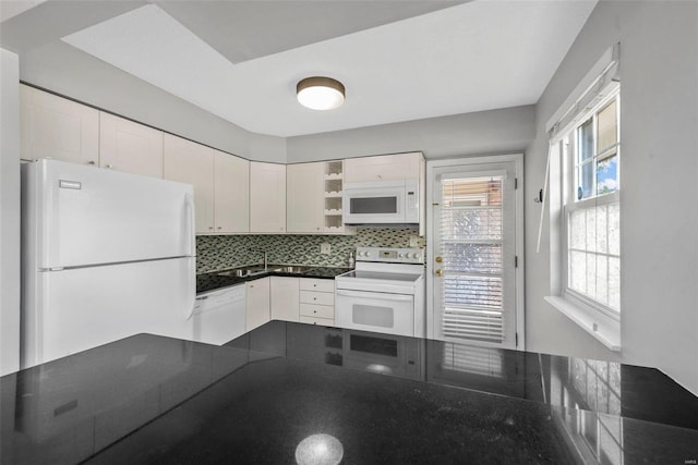 kitchen with kitchen peninsula, tasteful backsplash, white appliances, and white cabinetry