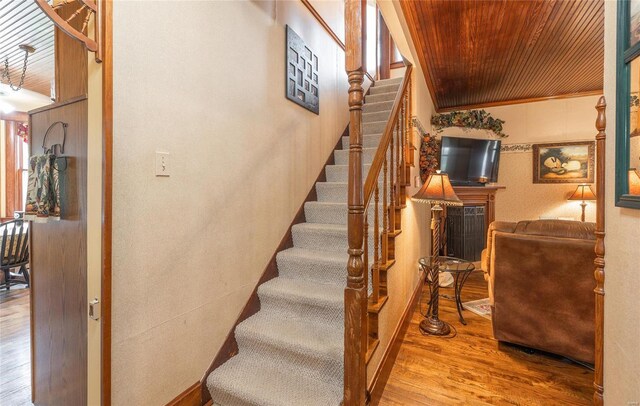 staircase featuring ornamental molding, wooden ceiling, and hardwood / wood-style flooring