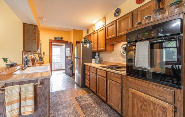 kitchen with dark hardwood / wood-style floors, sink, tasteful backsplash, and black appliances