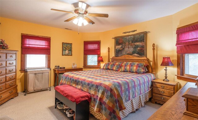 carpeted bedroom featuring multiple windows and ceiling fan