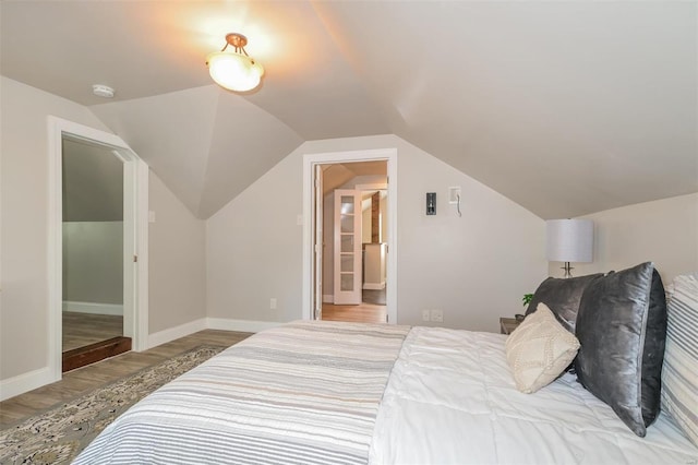 bedroom with light wood-type flooring and lofted ceiling