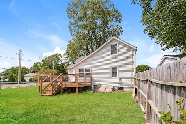 rear view of house with a wooden deck and a lawn