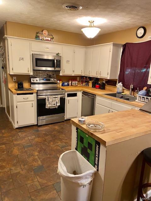 kitchen with appliances with stainless steel finishes, sink, and white cabinets