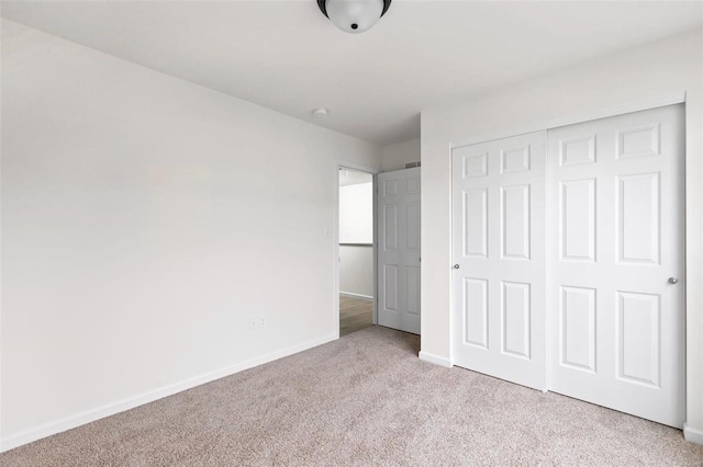 unfurnished bedroom featuring a closet and light colored carpet