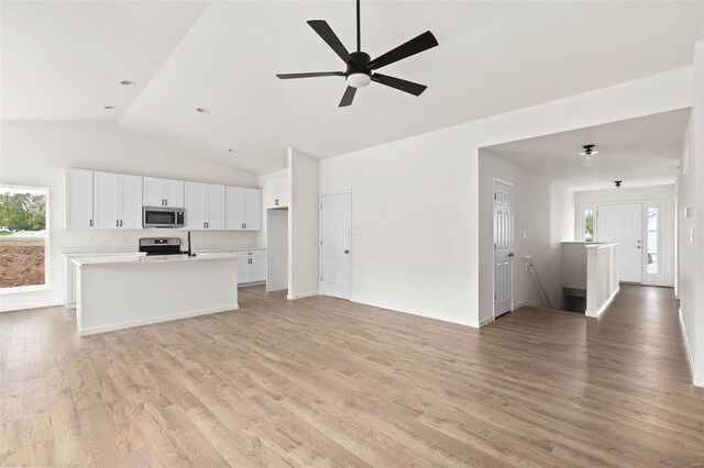 unfurnished living room with light wood-type flooring, ceiling fan, and vaulted ceiling