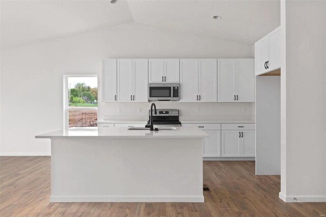 kitchen featuring lofted ceiling, stainless steel appliances, an island with sink, and white cabinetry