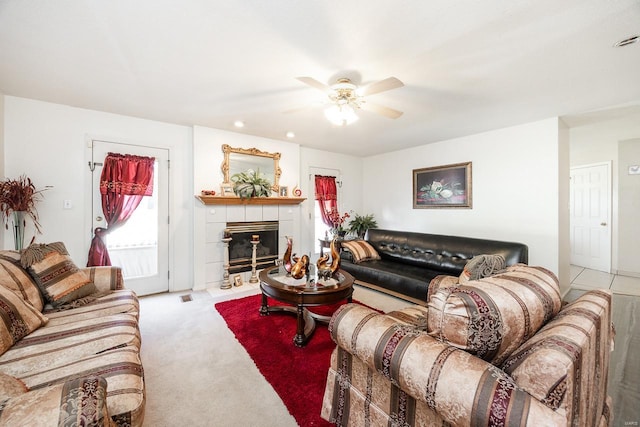 living room featuring a fireplace, light colored carpet, and ceiling fan