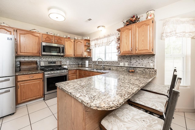 kitchen with stone countertops, stainless steel appliances, tasteful backsplash, and sink