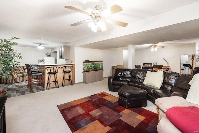 carpeted living room with a textured ceiling, bar area, and ceiling fan