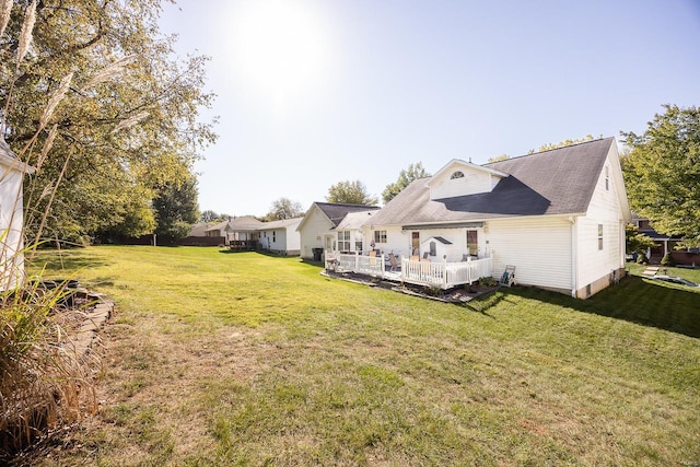 rear view of house featuring a wooden deck and a lawn