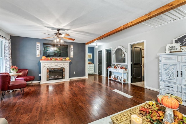 living room featuring beam ceiling, a premium fireplace, ceiling fan, and dark wood-type flooring