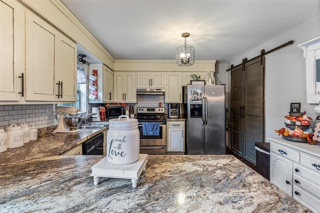 kitchen featuring cream cabinets, decorative backsplash, a barn door, decorative light fixtures, and stainless steel appliances