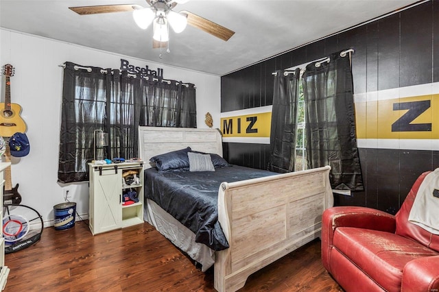 bedroom with dark hardwood / wood-style flooring, ceiling fan, and wood walls