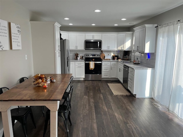 kitchen featuring backsplash, stainless steel appliances, white cabinetry, sink, and dark wood-type flooring