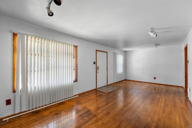 empty room with rail lighting, hardwood / wood-style flooring, and a wealth of natural light