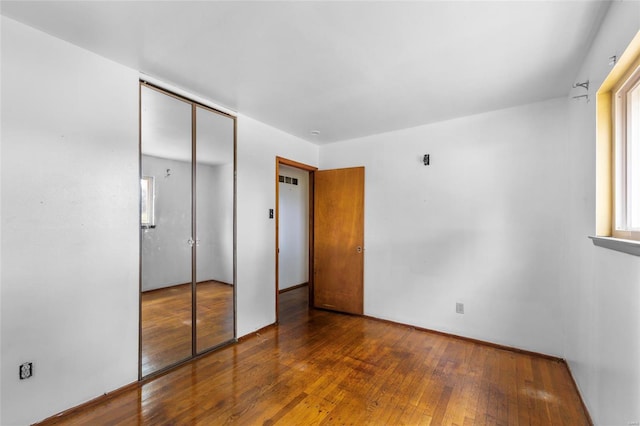 unfurnished bedroom with a closet and hardwood / wood-style flooring