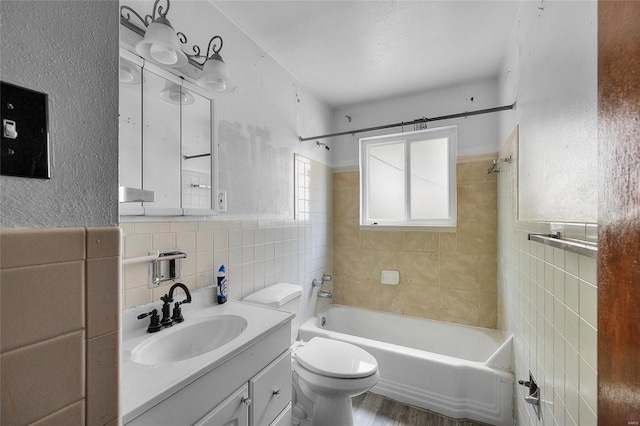 full bathroom with tiled shower / bath, hardwood / wood-style flooring, tile walls, toilet, and vanity