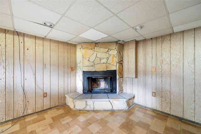 interior details featuring wooden walls, a fireplace, and a paneled ceiling