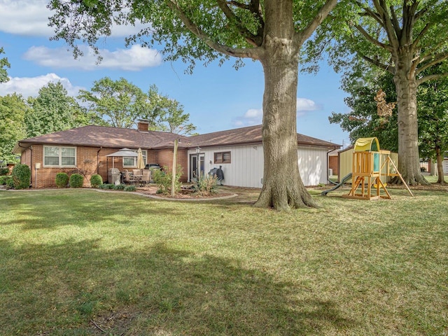 rear view of house with a playground and a yard