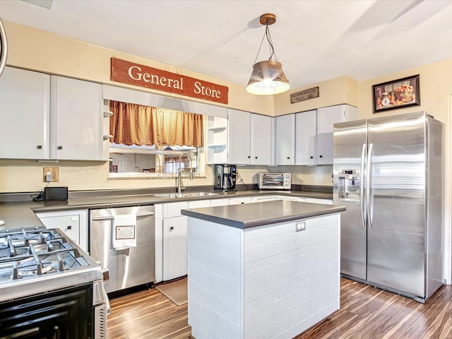 kitchen featuring stainless steel appliances, decorative light fixtures, hardwood / wood-style floors, a center island, and white cabinets