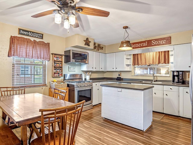 kitchen with stainless steel appliances, light wood-type flooring, hanging light fixtures, white cabinets, and ceiling fan