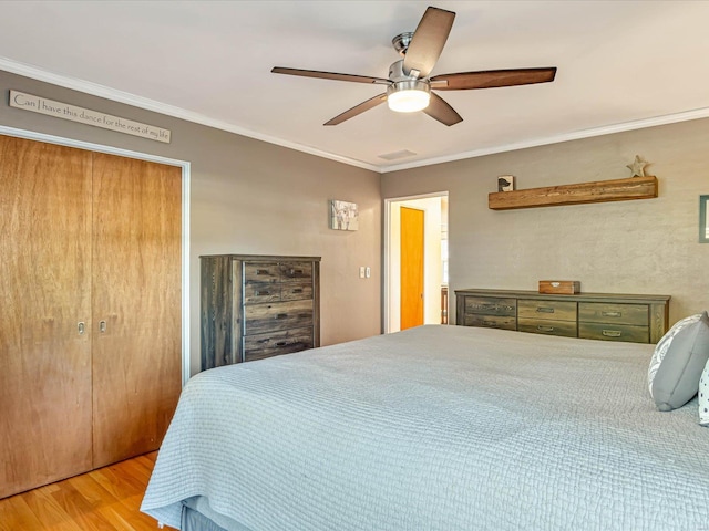 bedroom featuring hardwood / wood-style floors, ceiling fan, crown molding, and a closet